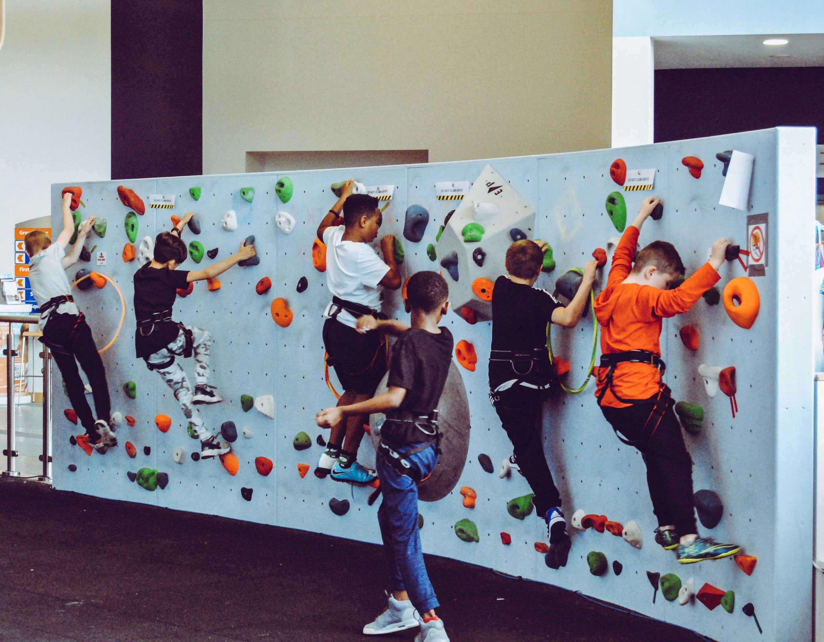 Children climbing on a colorful indoor rock climbing wall.